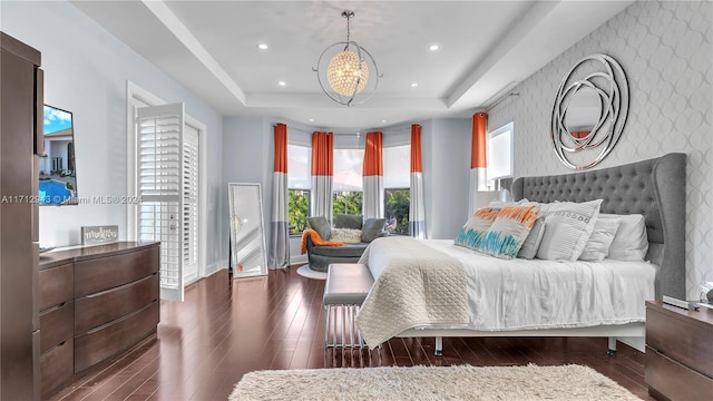 bedroom featuring a tray ceiling, an inviting chandelier, and dark wood-type flooring