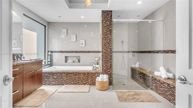 bathroom with tile patterned flooring, vanity, tile walls, and plus walk in shower