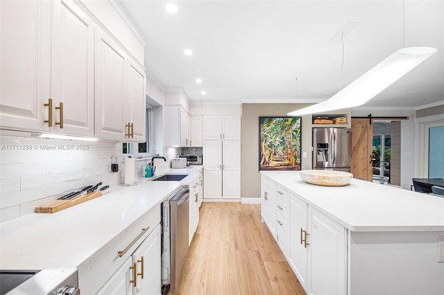 kitchen featuring appliances with stainless steel finishes, pendant lighting, a barn door, white cabinets, and a center island