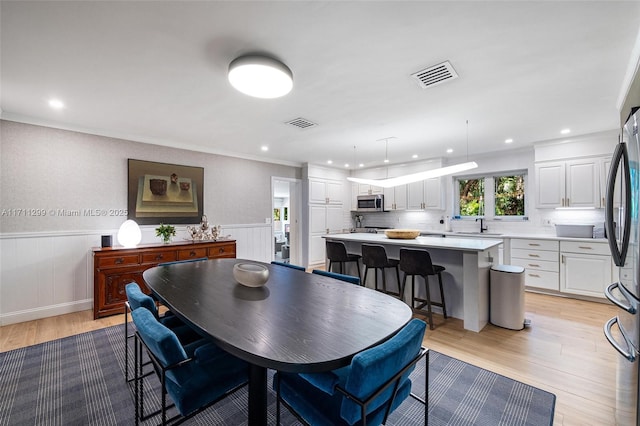 dining room featuring light hardwood / wood-style floors, crown molding, and sink