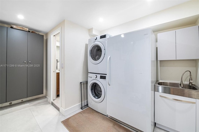 washroom with light tile patterned floors, stacked washing maching and dryer, and sink