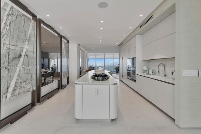 kitchen with a center island, a barn door, white cabinetry, and sink