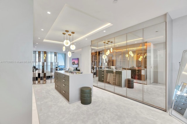 interior space with a raised ceiling, floor to ceiling windows, a kitchen island, and hanging light fixtures