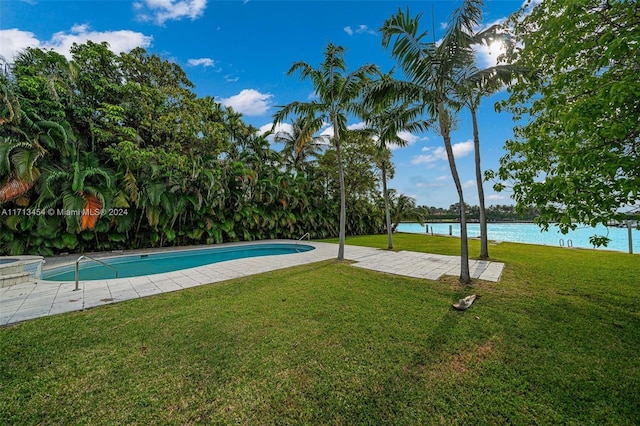 view of swimming pool featuring a yard, a water view, and a patio