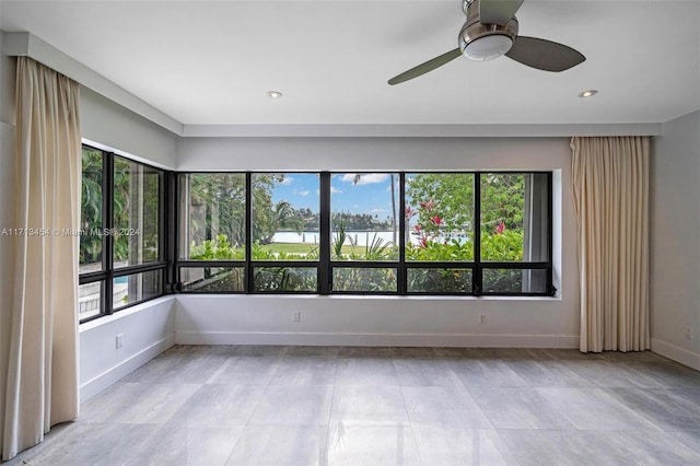 unfurnished room with ceiling fan and a wealth of natural light