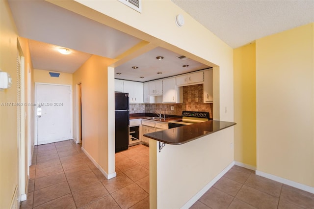 kitchen with light tile patterned floors, kitchen peninsula, decorative backsplash, white cabinets, and black appliances