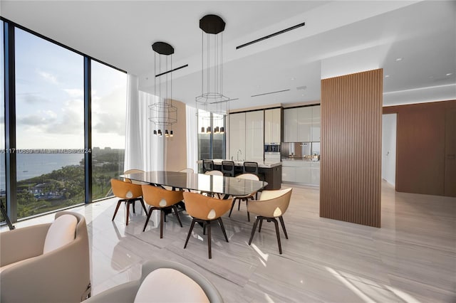 dining space with a water view, expansive windows, and light tile patterned floors