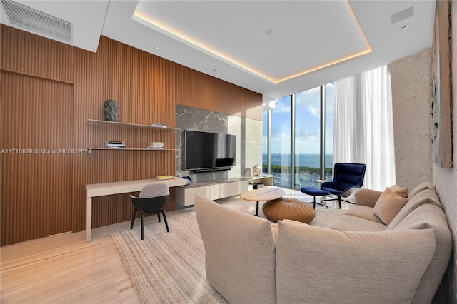 living room featuring wood walls, a wall of windows, and light hardwood / wood-style flooring