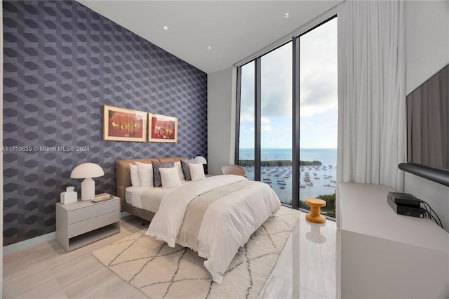 bedroom with access to outside, a water view, and floor to ceiling windows