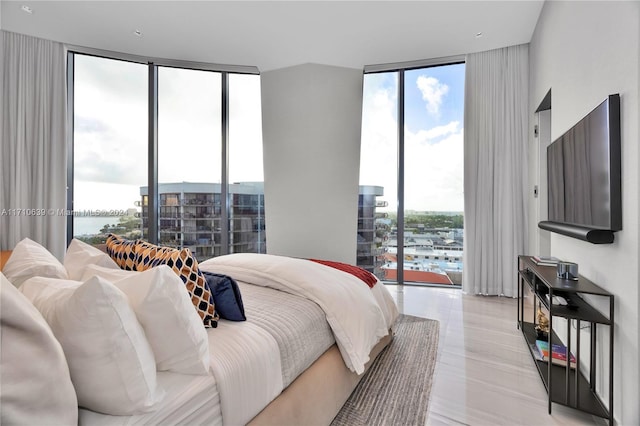 bedroom with multiple windows, access to outside, a wall of windows, and a water view