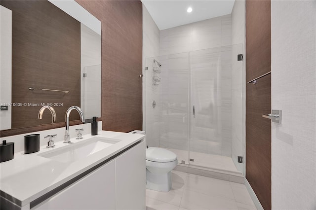 bathroom featuring tile patterned flooring, vanity, toilet, and a shower with door