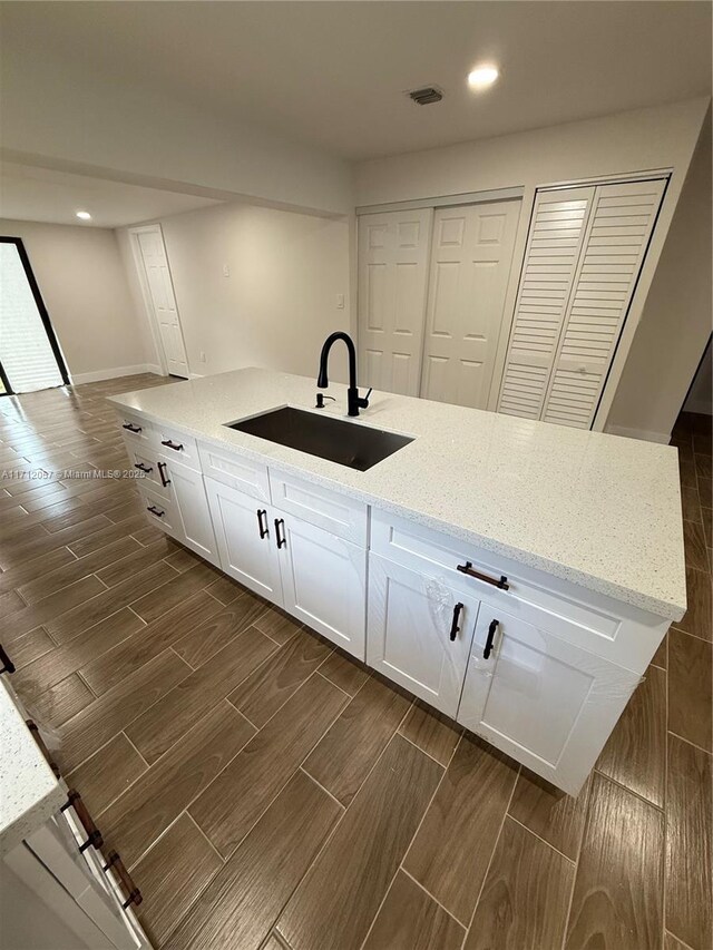 kitchen with sink, light stone counters, and white cabinetry