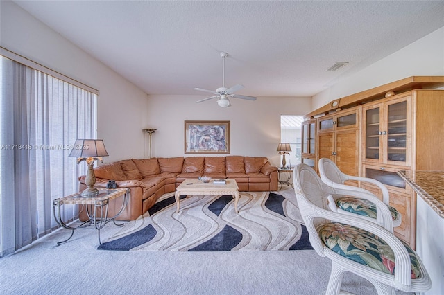 living room with ceiling fan, carpet, and a textured ceiling