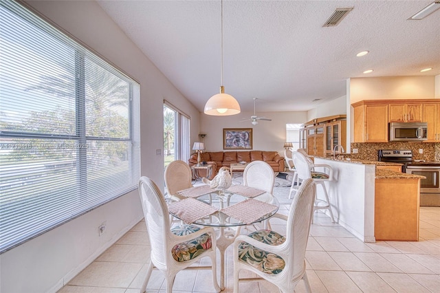 dining area with sink, light tile patterned floors, and a textured ceiling