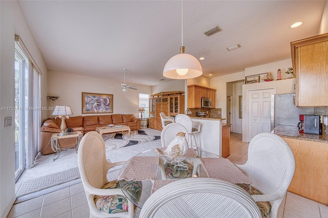 tiled dining space with a textured ceiling and ceiling fan