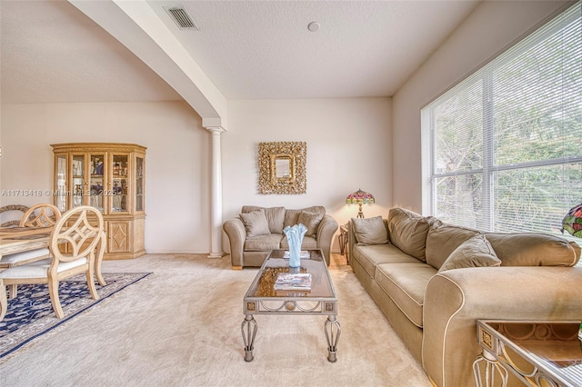 living room with a textured ceiling, light colored carpet, and ornate columns