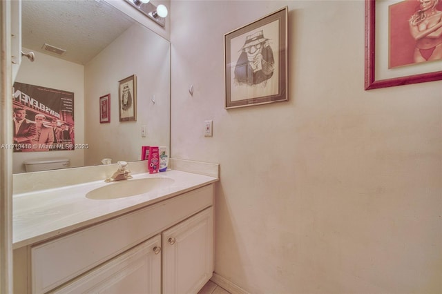 bathroom with vanity, a textured ceiling, and toilet