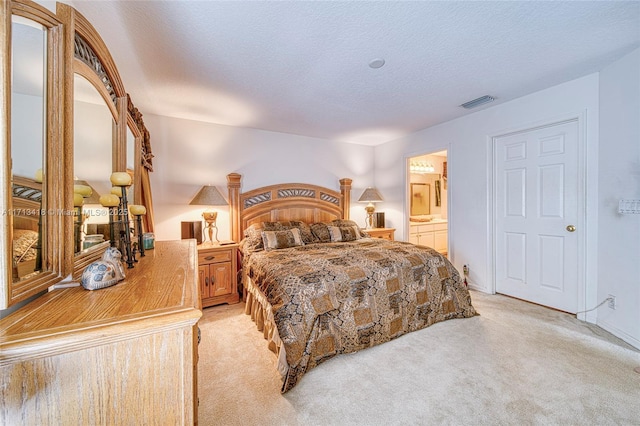 carpeted bedroom with ensuite bathroom and a textured ceiling