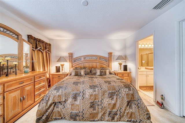 bedroom with light colored carpet, a textured ceiling, and connected bathroom