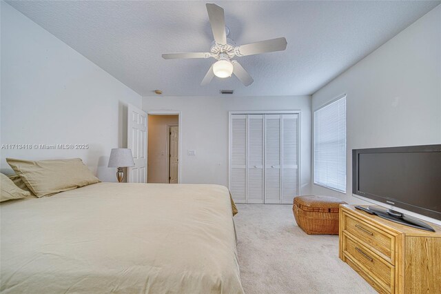 carpeted bedroom with ceiling fan and a textured ceiling