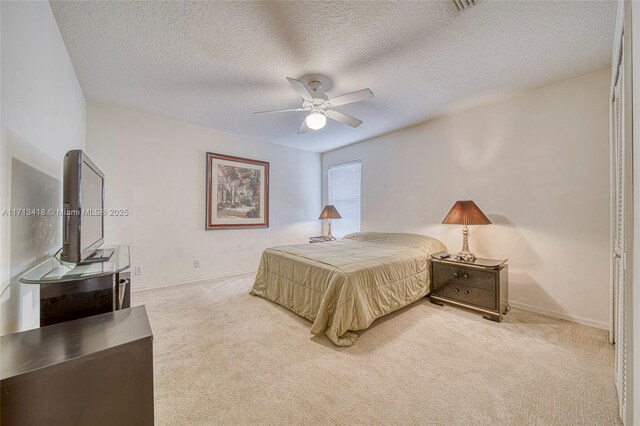 bedroom featuring ceiling fan, light colored carpet, a textured ceiling, and a closet