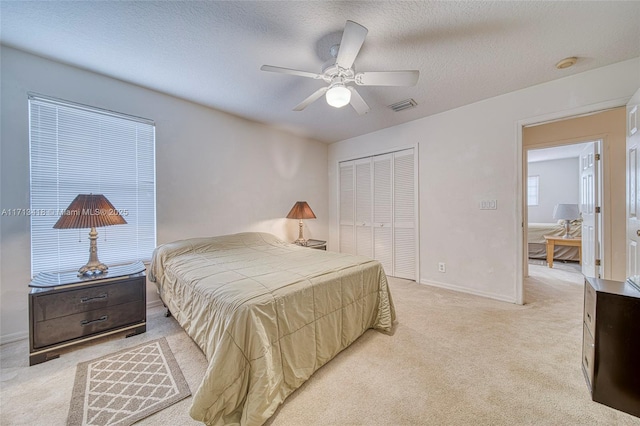 carpeted bedroom featuring ceiling fan, a textured ceiling, and a closet