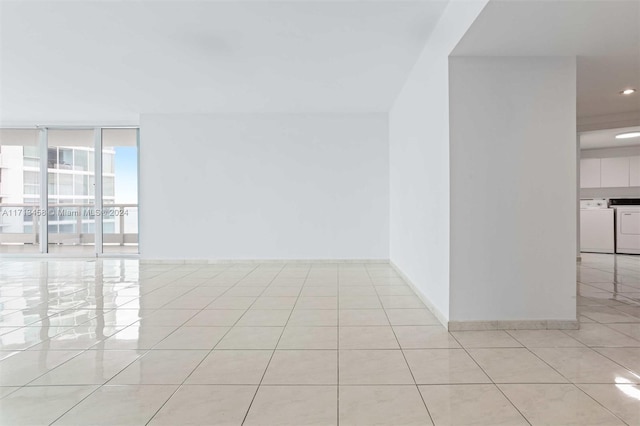 tiled empty room featuring floor to ceiling windows and independent washer and dryer