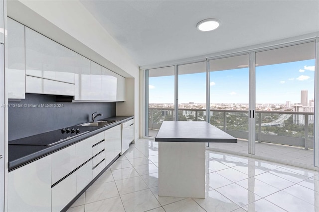 kitchen with dishwasher, expansive windows, sink, a kitchen island, and white cabinetry