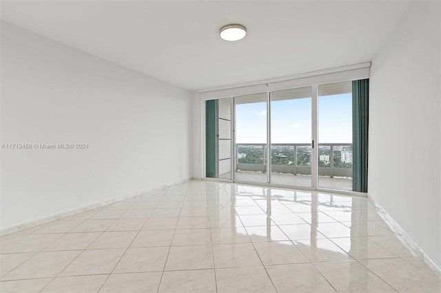 unfurnished room with light tile patterned floors and a wall of windows