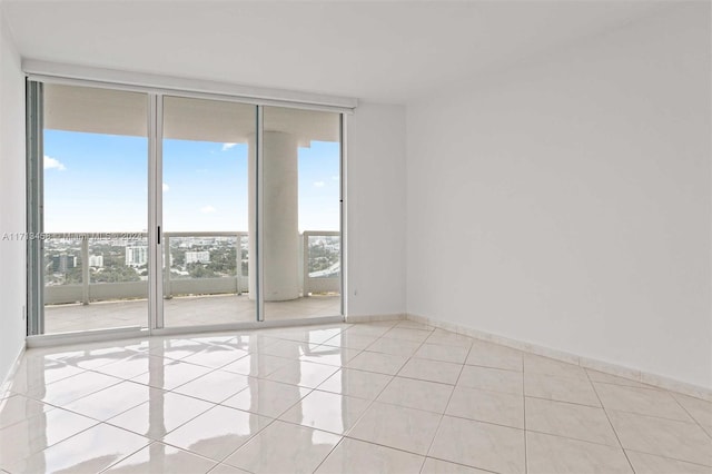 spare room featuring expansive windows and light tile patterned floors