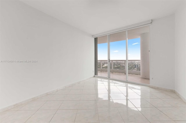 unfurnished room featuring light tile patterned flooring and a wall of windows