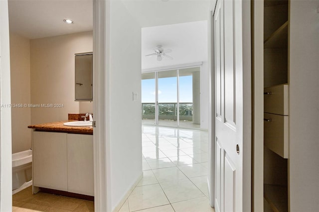 corridor with light tile patterned flooring, expansive windows, and sink