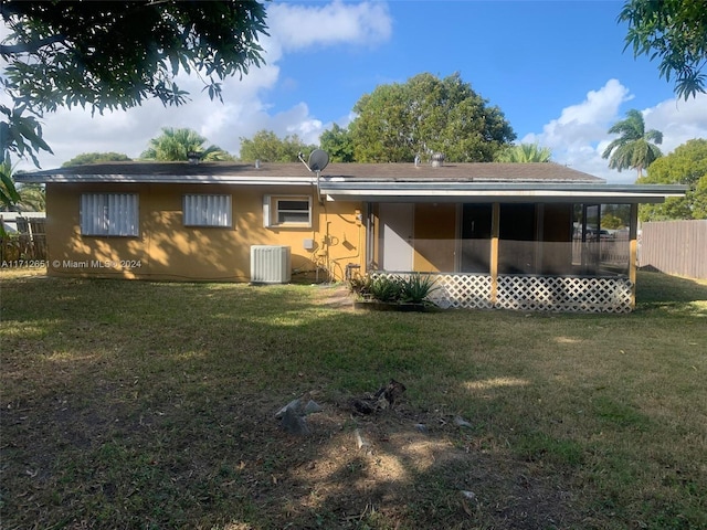 back of property with central AC unit and a lawn