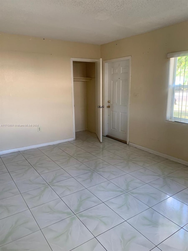 unfurnished bedroom featuring a textured ceiling and a closet