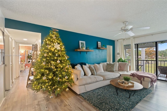 living room with ceiling fan, light hardwood / wood-style floors, and a textured ceiling