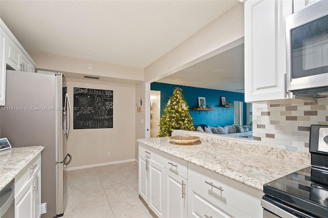 kitchen with backsplash, white cabinetry, stainless steel appliances, and a textured ceiling