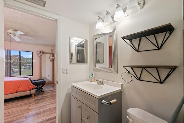 bathroom with vanity, hardwood / wood-style flooring, ceiling fan, toilet, and a textured ceiling