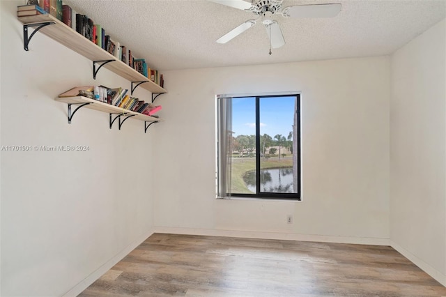 spare room featuring ceiling fan, light hardwood / wood-style floors, and a textured ceiling