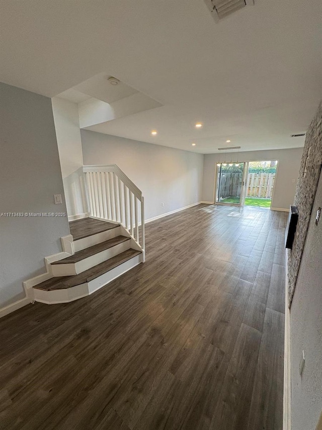 interior space featuring baseboards, visible vents, wood finished floors, and stairway