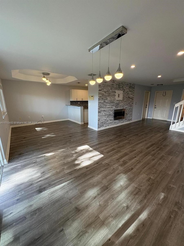 unfurnished living room with a fireplace, dark hardwood / wood-style floors, and ceiling fan