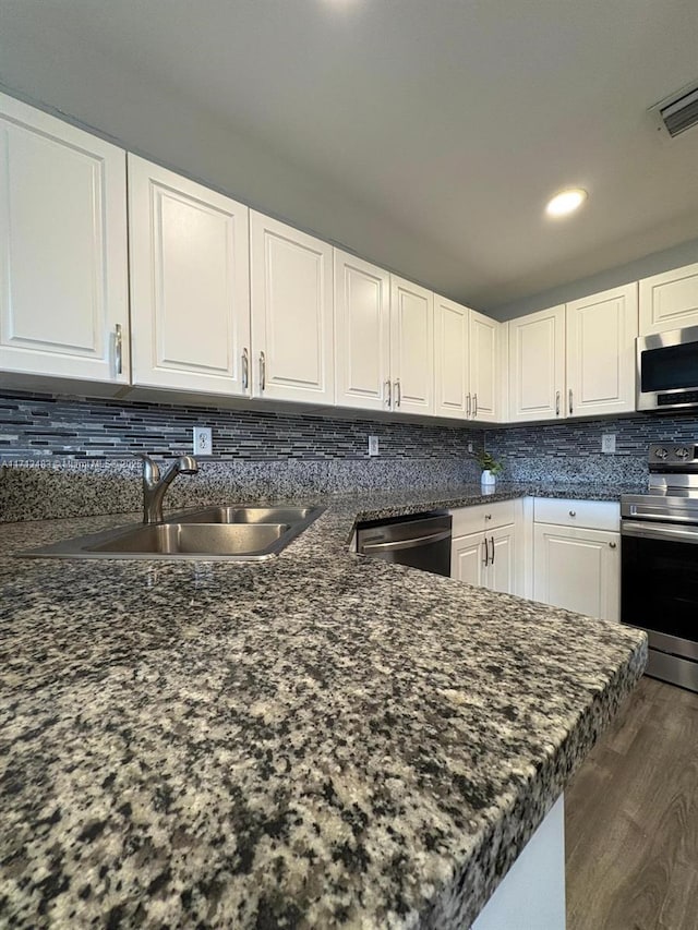 kitchen featuring decorative backsplash, white cabinets, visible vents, stainless steel appliances, and a sink