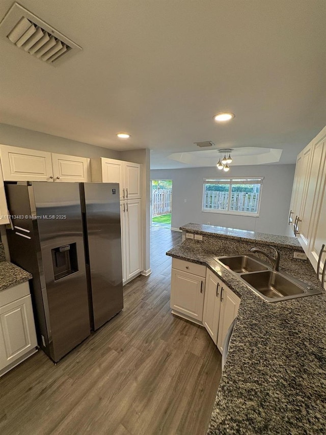 kitchen featuring stainless steel fridge with ice dispenser, a sink, visible vents, white cabinets, and wood finished floors