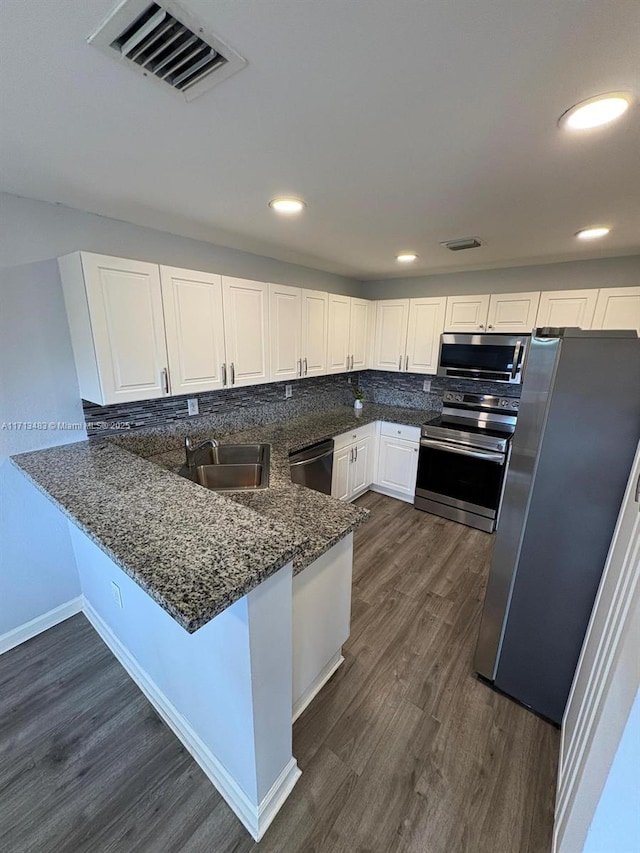 kitchen with sink, stainless steel appliances, dark wood-type flooring, kitchen peninsula, and white cabinets