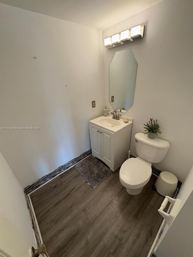 bathroom with toilet, wood finished floors, and vanity