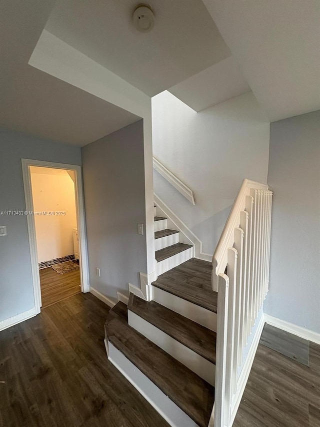staircase featuring baseboards and wood finished floors