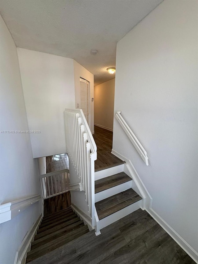 stairs featuring a textured ceiling and hardwood / wood-style flooring