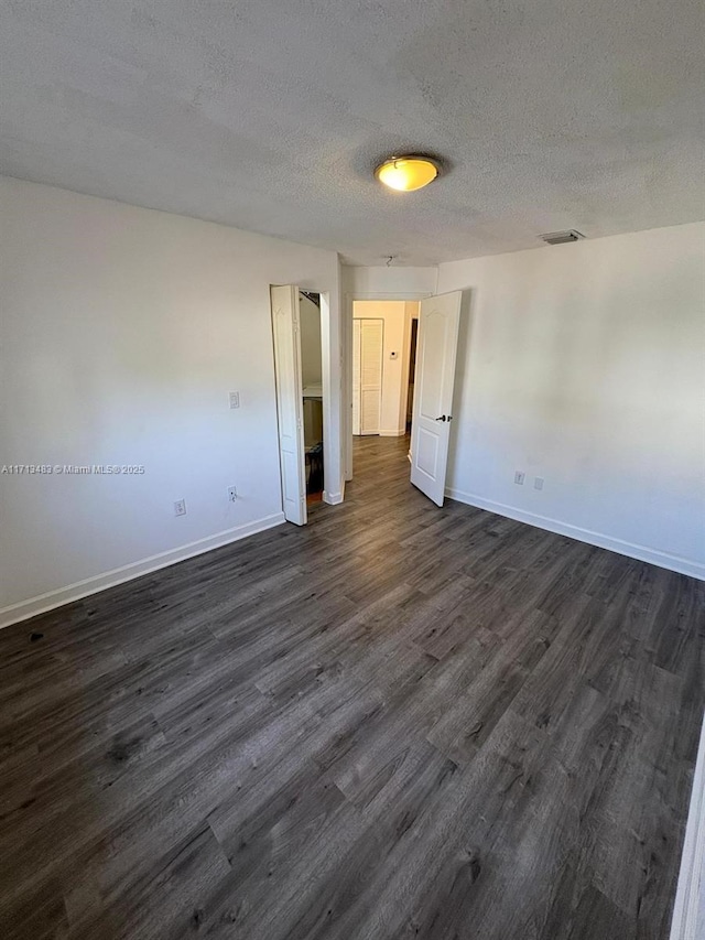 empty room featuring a textured ceiling and dark hardwood / wood-style floors