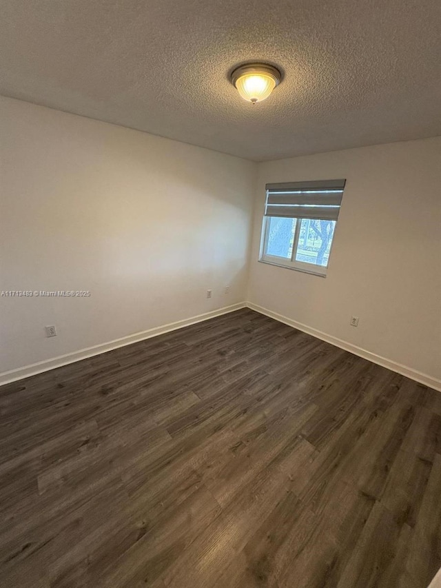 spare room featuring a textured ceiling and dark wood-type flooring