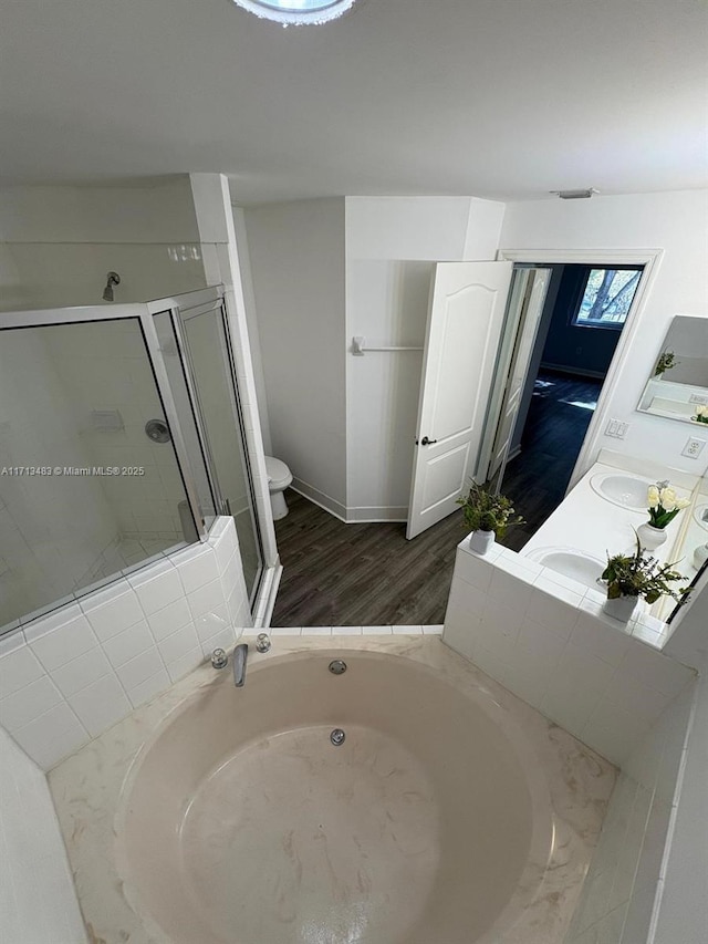 full bath with a shower stall, toilet, wood finished floors, vanity, and a garden tub