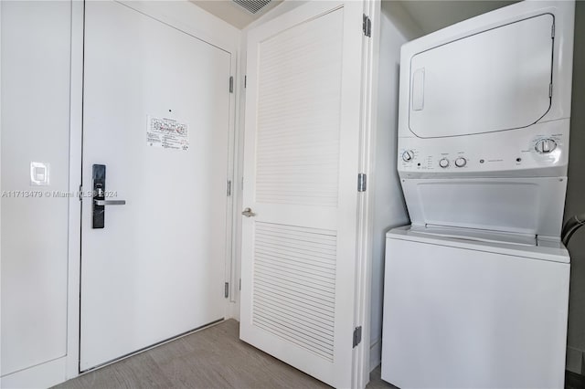 laundry room featuring light hardwood / wood-style floors and stacked washer and clothes dryer